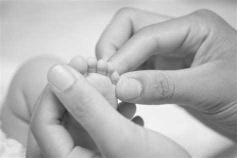 Mani di un adulto che cullano i piedi di un neonato