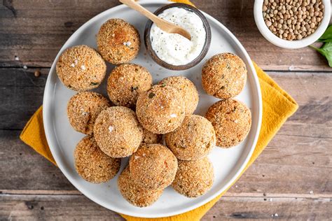 Piatto invitante di polpette di lenticchie dorate servite con salse e guarnizioni fresche