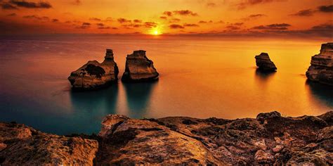Panorama suggestivo del mare del Salento al tramonto con sfumature arancioni e blu