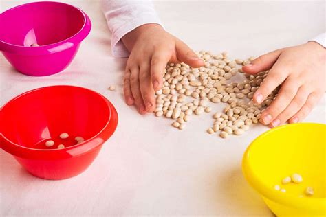 bambina di due anni che utilizza un gioco di travasi
