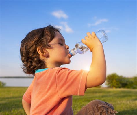 Bambino che fa sport e beve da una borraccia