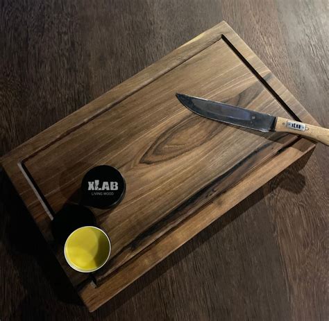 Una panoramica ravvicinata di funghi ovuli ancora integri su un tagliere di legno, accanto a un coltellino da cucina professionale e un pennello per la pulizia.