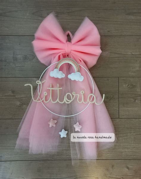 rappresentazione grafica di un fiocco nascita in tulle appeso a una porta con decorazioni floreali