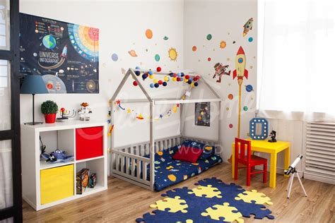 Bambino che gioca autonomamente in una cameretta Montessori con un lettino basso
