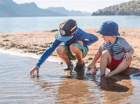 bambini che giocano in spiaggia protetti da abbigliamento solare