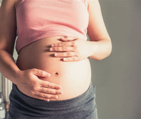 Mani di genitori che accarezzano la pancia di una mamma incinta, con un'icona di battito cardiaco sullo sfondo