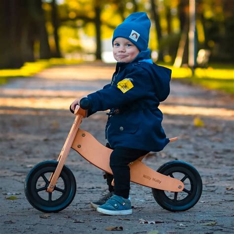Bambino che gioca con una balance bike in legno in un parco