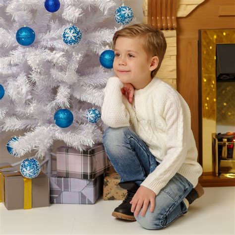 Un bambino piccolo vicino a un albero di Natale circondato da doni delicati e naturali