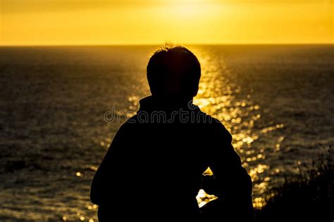 Bambino che guarda l'orizzonte al tramonto