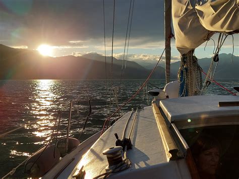 Donna incinta sorridente su una barca a vela al tramonto