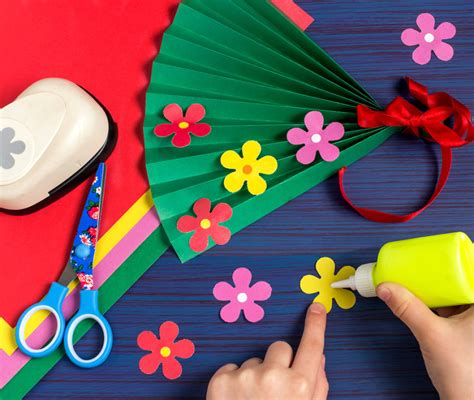 Tavolo con vari materiali per il fai da te: cartoncini colorati, forbici, colla, nastri, bottoni