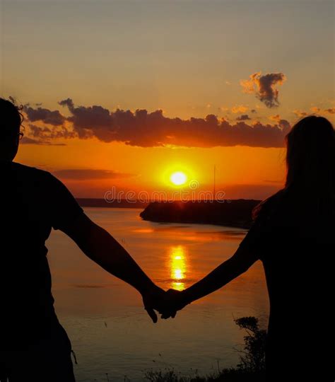 Coppia incinta che cammina mano nella mano al tramonto