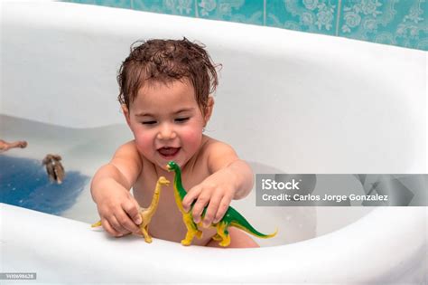 Bambino di 8 anni che gioca in una vasca da bagno con acqua colorata e giocattoli