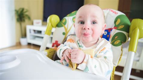 Bambino di 6 mesi seduto nel seggiolone durante lo svezzamento