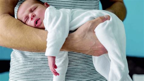 Neonato a pancia in giù sul grembo del genitore