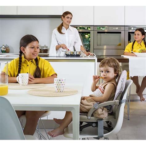 Bambino felice seduto sul rialzo sedia Cam Smarty Pop al tavolo