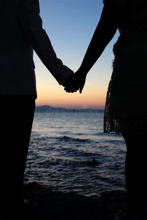 coppia che si tiene per mano guardando il tramonto
