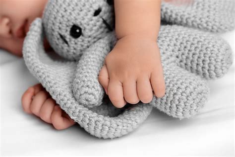 Neonato che abbraccia un doudou