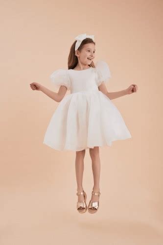Bambina con vestito elegante bianco su un prato
