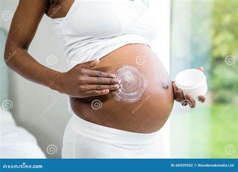 Pregnant woman applying cream on her belly