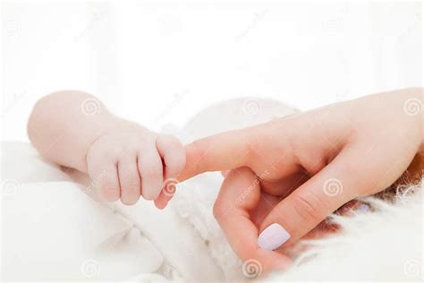 Illustrazione di un neonato che afferra un dito di un adulto, con un raggio di sole che entra dalla finestra