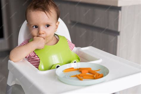 Bambino che gioca con il cibo sul vassoio regolabile di un seggiolone