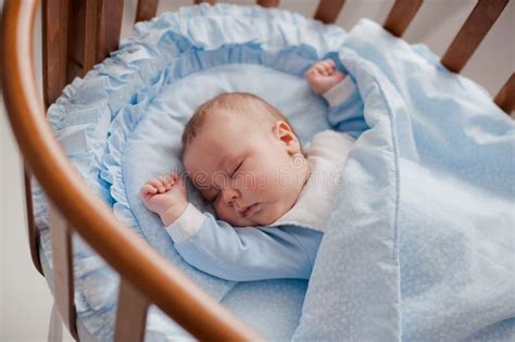 Bambino che dorme in una culla con lenzuola ricamate