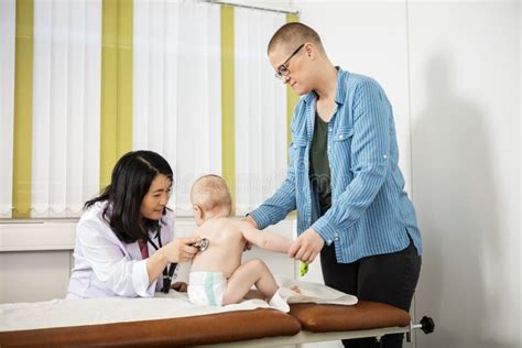 Pediatra che esamina un neonato mentre la madre guarda