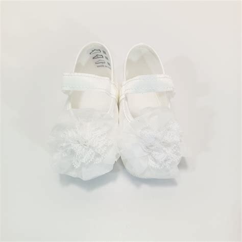 Un set di delicate scarpine battesimali realizzate all'uncinetto adagiate su un pizzo bianco