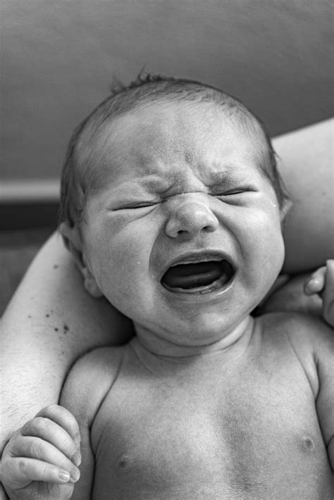 neonato che piange tra le braccia del genitore