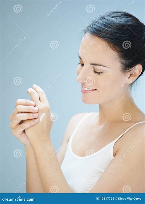 Donna in gravidanza che si massaggia le mani con una crema