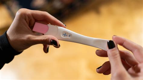 Uomo che tiene la mano della partner mentre guardano un test di gravidanza positivo