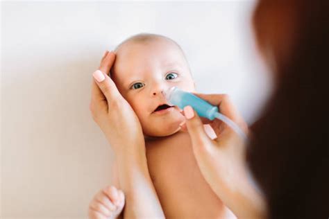 Bambino che usa un aspiratore nasale