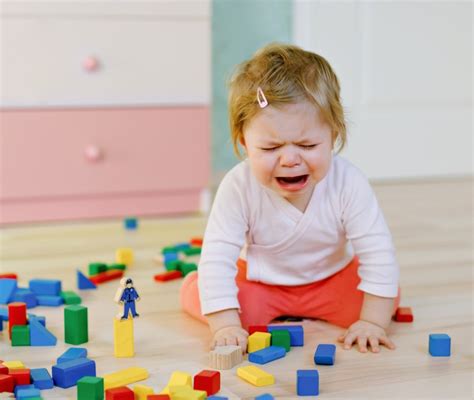 Bambino che piange mentre si aggrappa alla gamba del genitore all'ingresso del nido