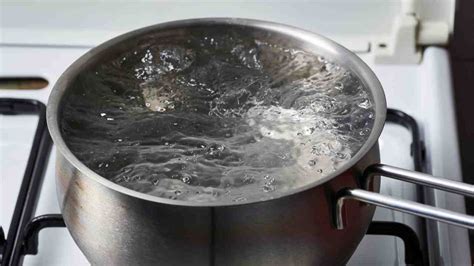 pentola con acqua che bolle contenente le parti di un biberon