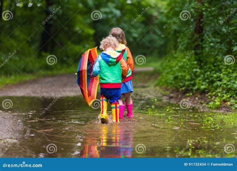 Bambini che giocano con stivali da pioggia nelle pozzanghere