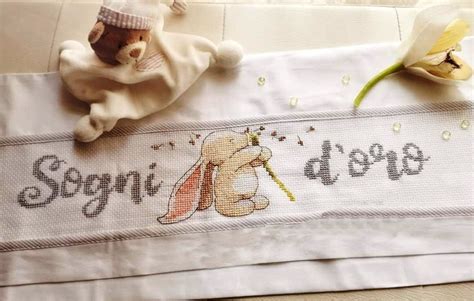 cuscino neonato ricamato a punto croce in una culla bianca