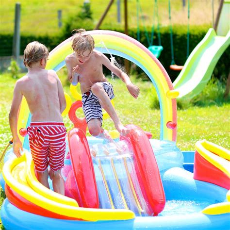 bambini che giocano in una piscina gonfiabile colorata in un giardino soleggiato