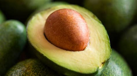 Un avocado maturo tagliato a metà con il nocciolo in vista su una tavola di legno