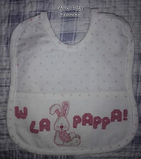 esempio di bavaglino ricamato con un nome e decorazioni floreali a punto croce