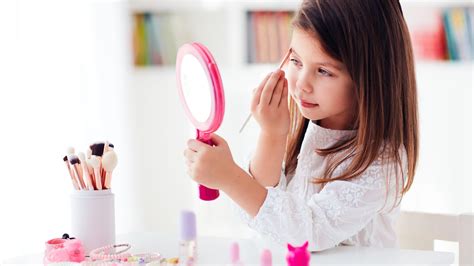 Bambina che si trucca davanti a uno specchio con una valigetta di trucchi per bambini