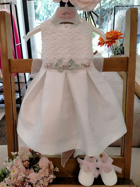 Bambina che indossa un elegante abito da battesimo Mimilù in un giardino fiorito