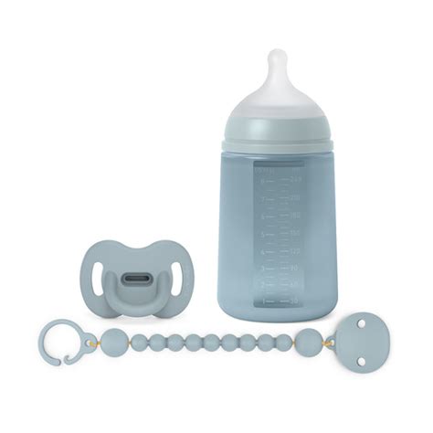 Un set completo di puericultura Suavinex, inclusa la catenella, su una superficie neutra