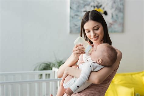 Bambino che si nutre al seno e un biberon di latte artificiale