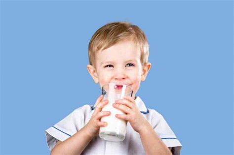 Bambino che beve il latte a colazione