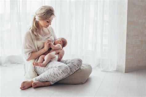 Mamma che allatta il neonato nella culla co-sleeping accanto al letto