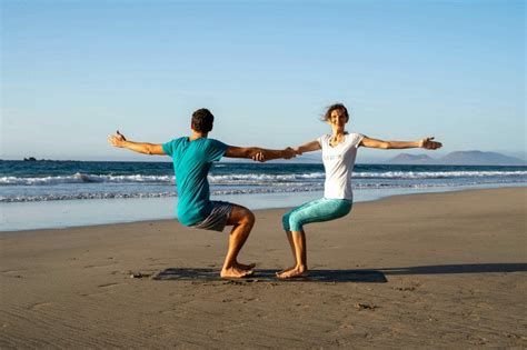 Coppia in babymoon che fa yoga in una località tropicale