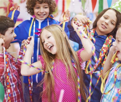 Bambini mascherati che sfilano durante una festa di Carnevale, con genitori e insegnanti che li accompagnano