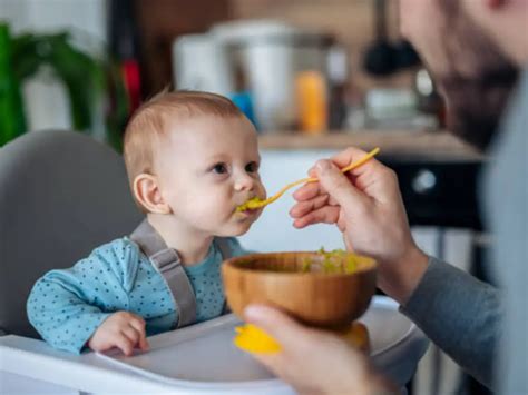 Bambino sorridente seduto a tavola con la famiglia sul seggiolone