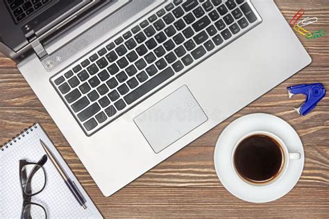 Una scrivania con un computer portatile, un libro aperto e una tazza di caffè